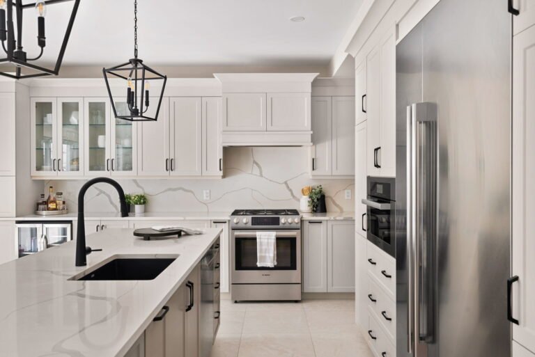 Elegant white kitchen remodel with marble countertops and stainless appliances by Designs by D and J.