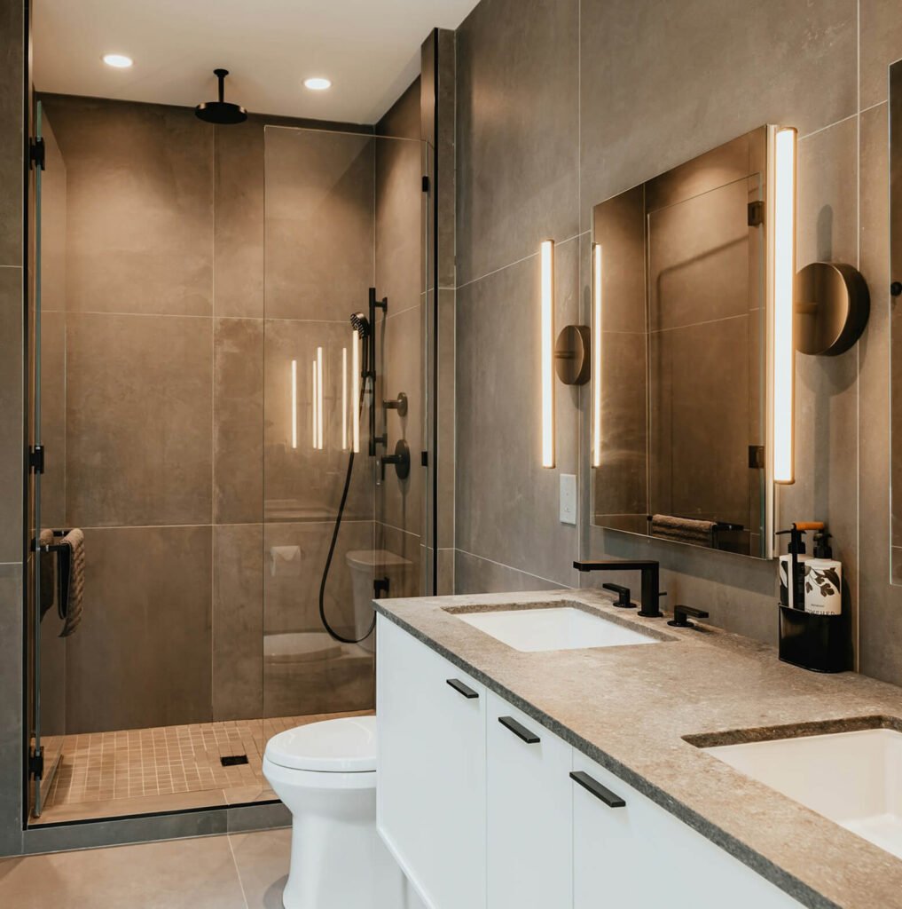 Modern bathroom renovation with warm lighting and custom vanity by Designs by D and J in NYC.